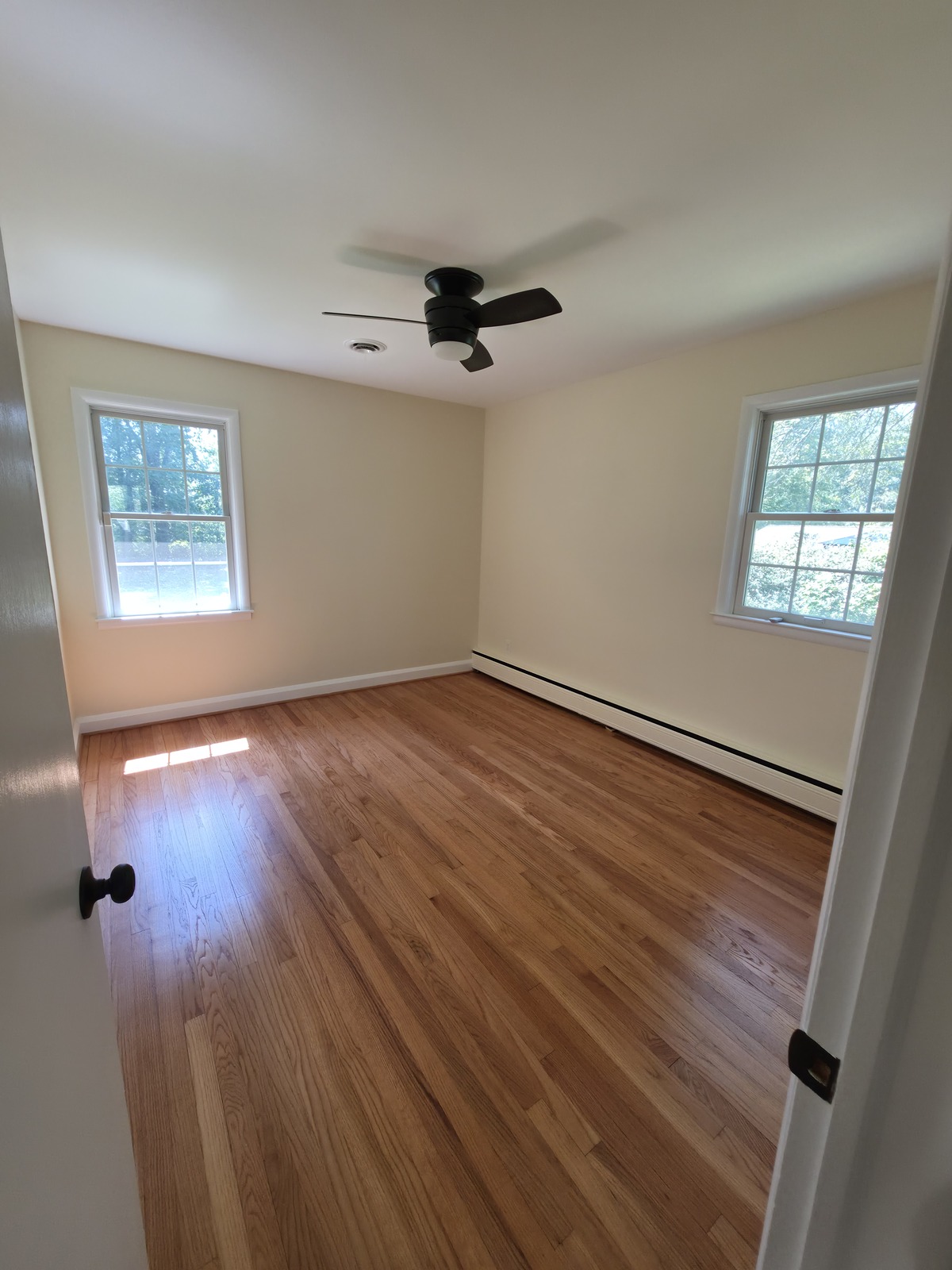 Bedroom from the featured project, with painted walls, ceiling and trim and refinished hardwood