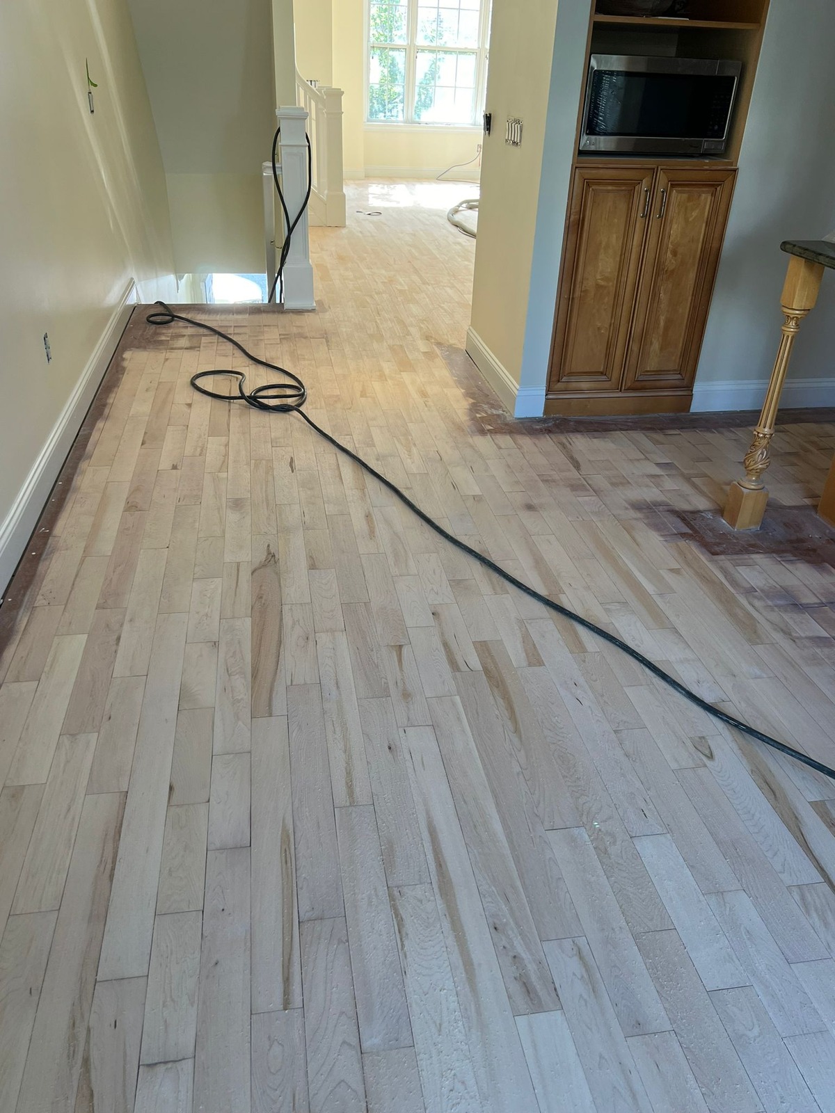 Wood floor sanding in progress, with a lighter sanded center and darker edges