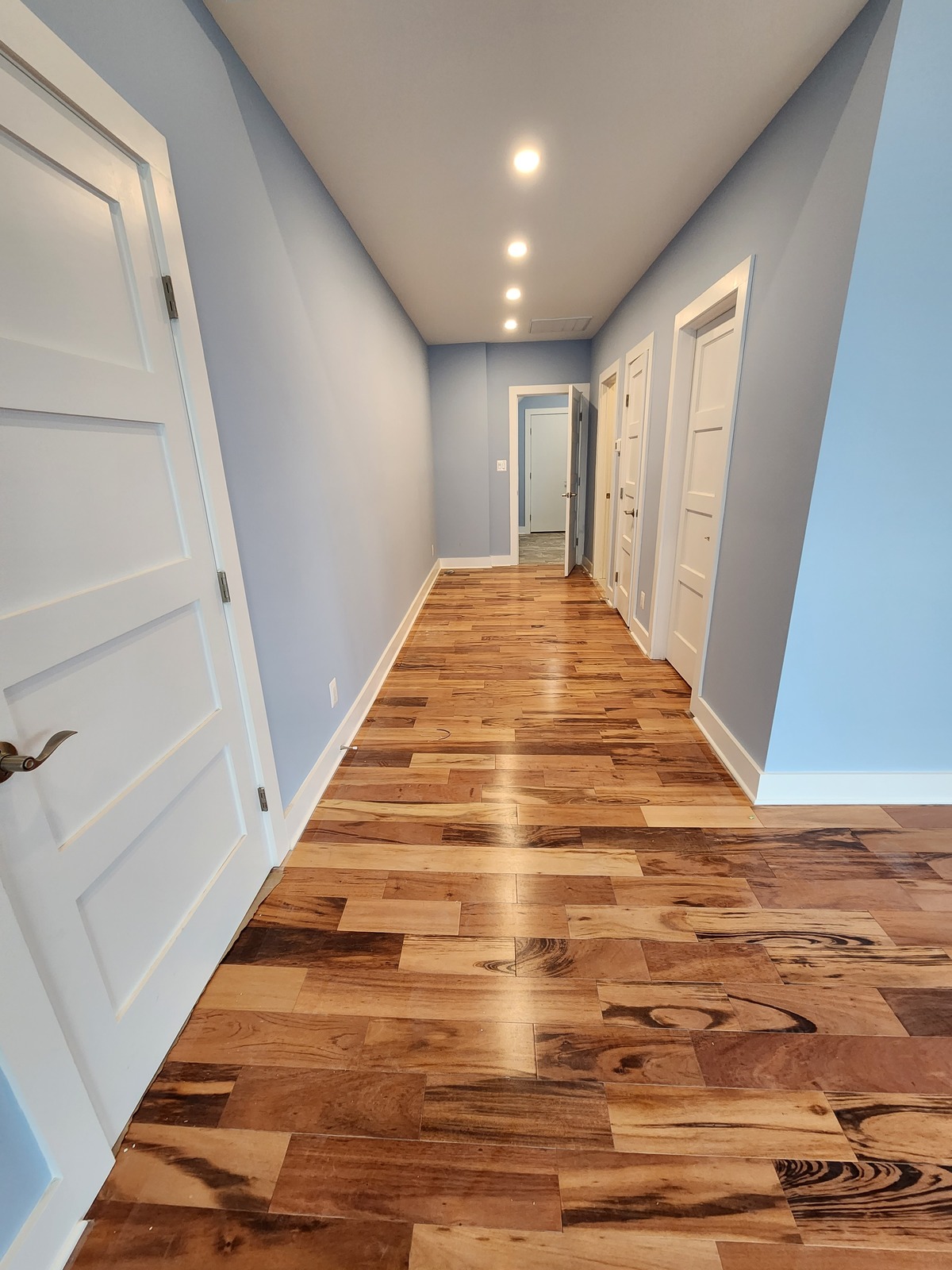 Blue-gray hallway walls with white doors, trim and baseboards
